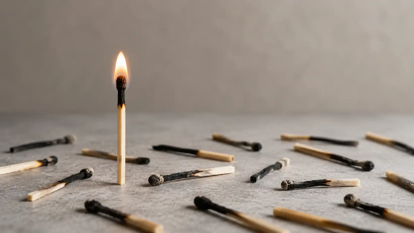 Cerillo encendido de pie rodeado de cerillos quemados como concepto de resiliencia liderazgo o última oportunidad