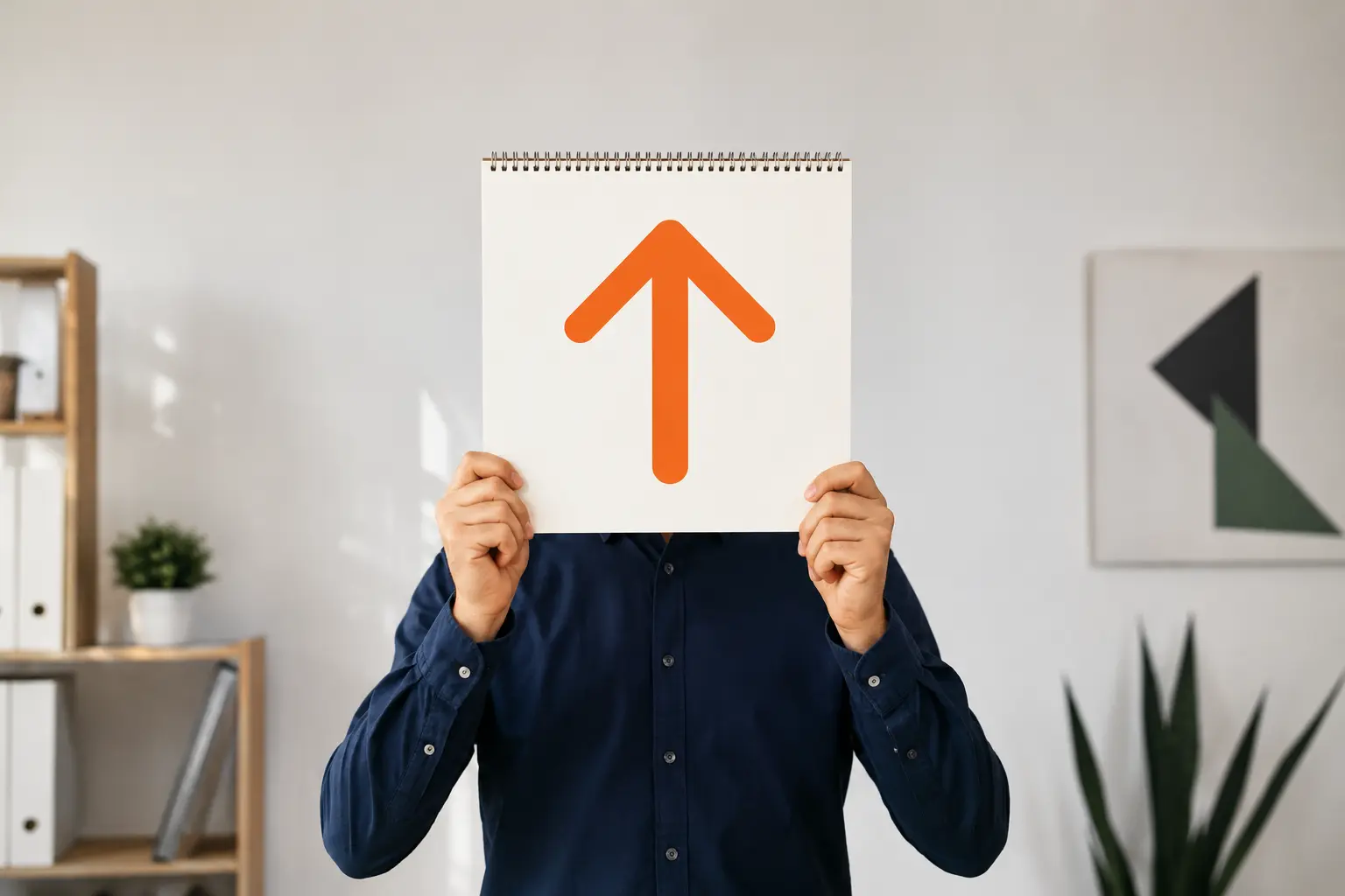 Hombre con camisa azul sosteniendo libreta con flecha naranja hacia arriba como concepto de crecimiento o mejora